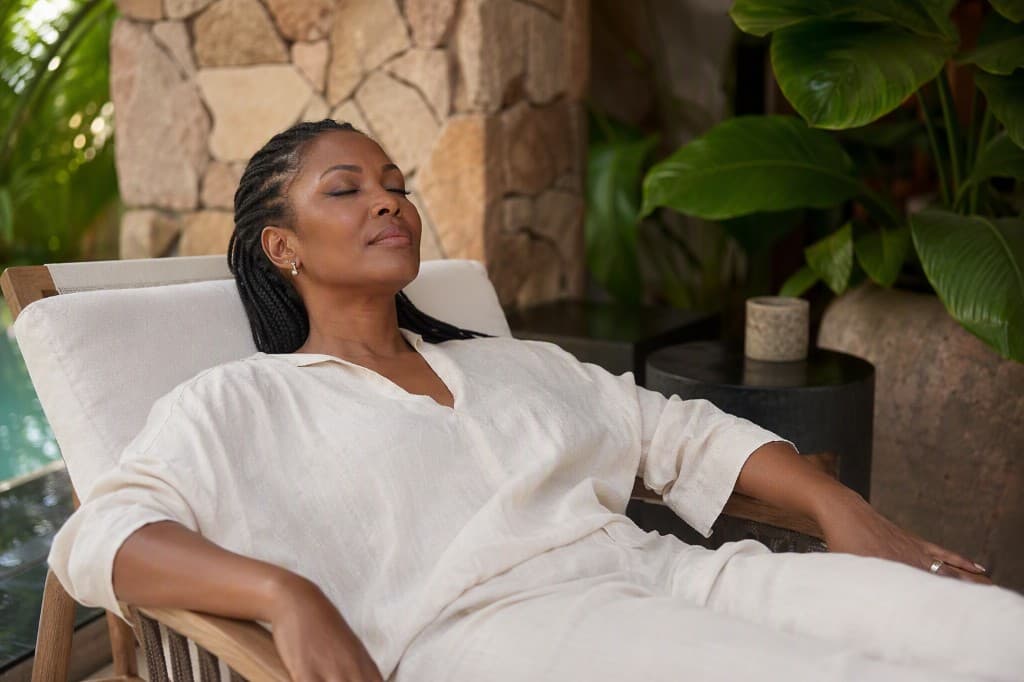 A woman relaxing outdoors in a lounge chair with her eyes closed